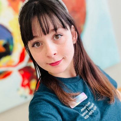 Sarah Veterinary Receptionist, female with long brown hair and bangs posing for picture